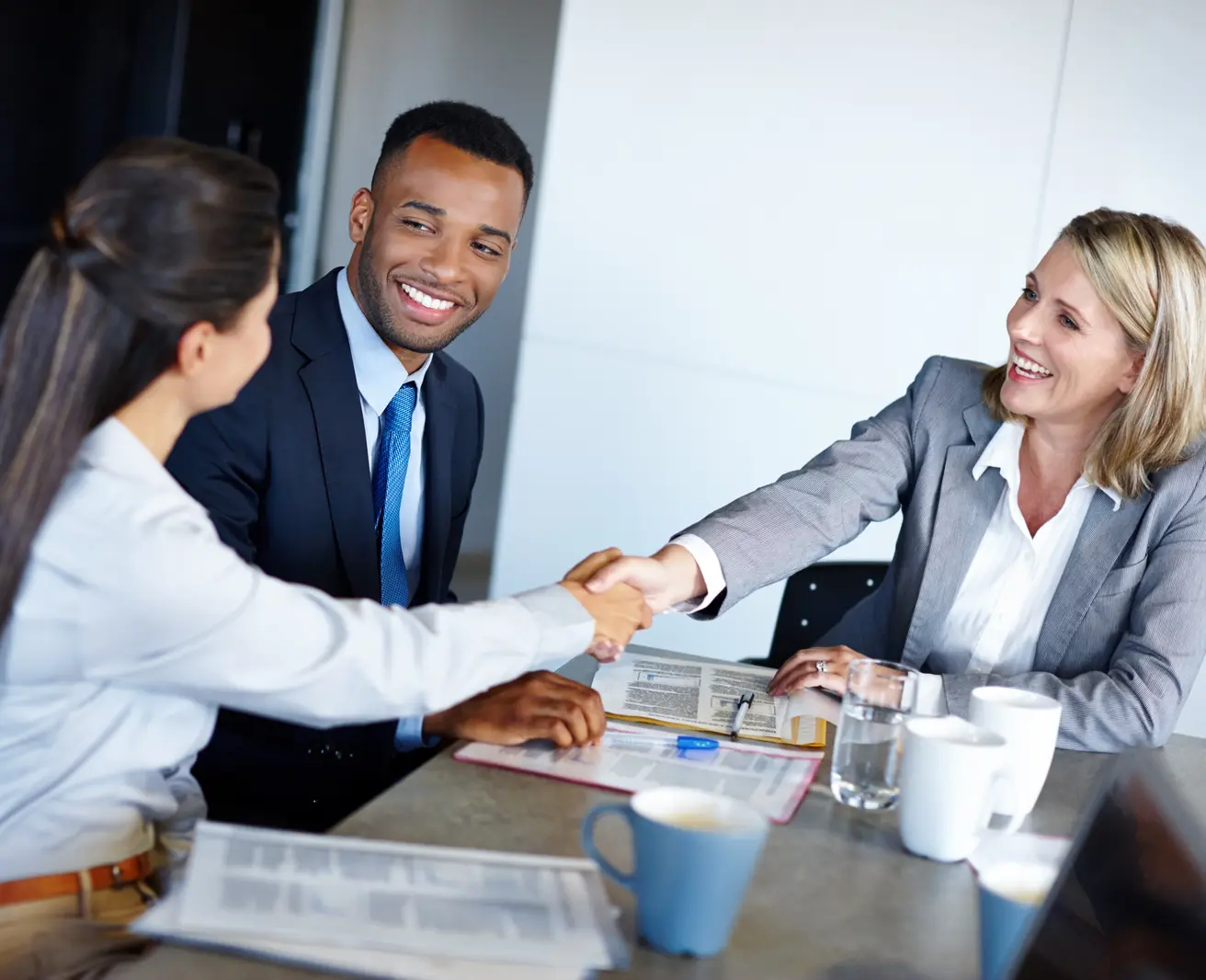A job candidate seated across a boardroom table from two interviewers in business attire
